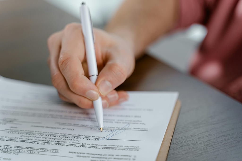 hand holding a pen writing on a Power of Attorney document.